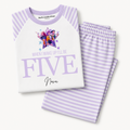 A children's pajama set laid flat on a light gray background, featuring a white long-sleeve top with lavender trim and a colorful graphic with the text 'When I wake up I'll be five' and matching large 'FIVE' lettering, paired with lavender-and-white striped pants.