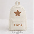 An off-white canvas backpack with a brown star on the front and the word 'JUNIOR' printed in brown below the zipper, shown against a light gray background.
